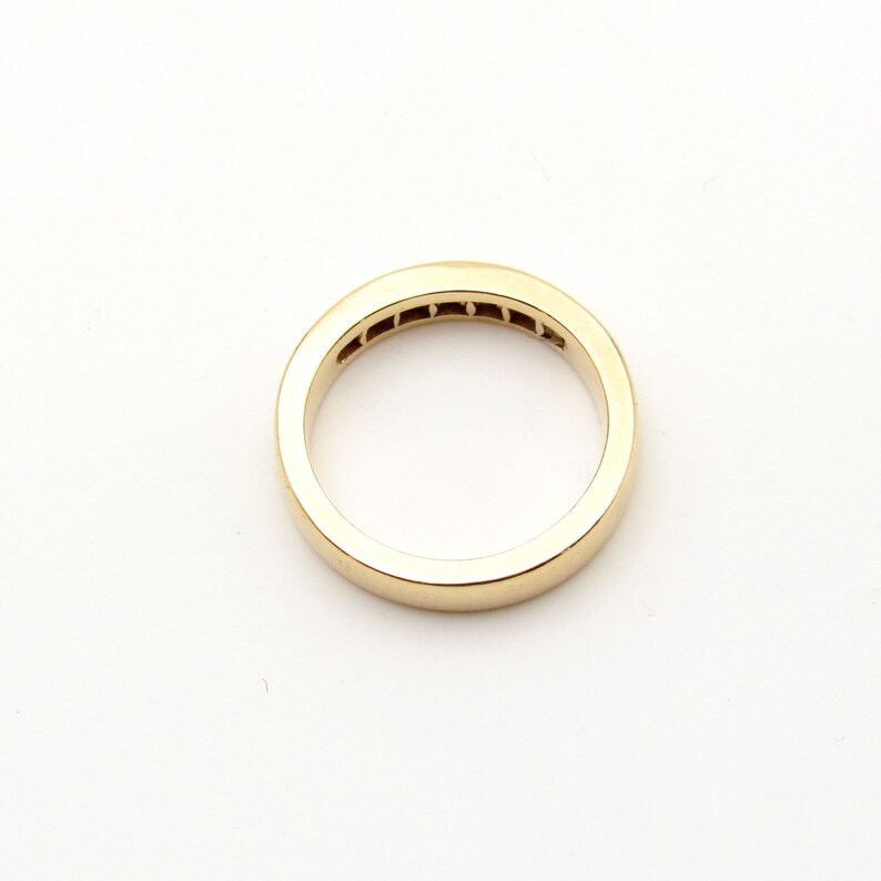 K&ouml;nnte beinhalten: Ein Goldring mit einer Reihe kleiner Diamanten, die in der Mitte eingesetzt sind.