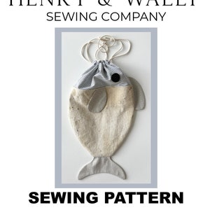 May include: A fish-shaped drawstring bag sewing pattern. The bag is made of beige fabric with gray accents and a striped top. The design includes a black eye and gray fins. The text "HENRY & WALLY SEWING COMPANY" and "SEWING PATTERN FISH DRAWSTRING BAG" are visible.