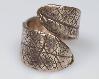 May include: A bronze ring with a leaf design. The ring is adjustable and can be worn on any finger.