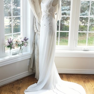 May include: A white wedding dress with a long train and floral embroidery on the bodice.