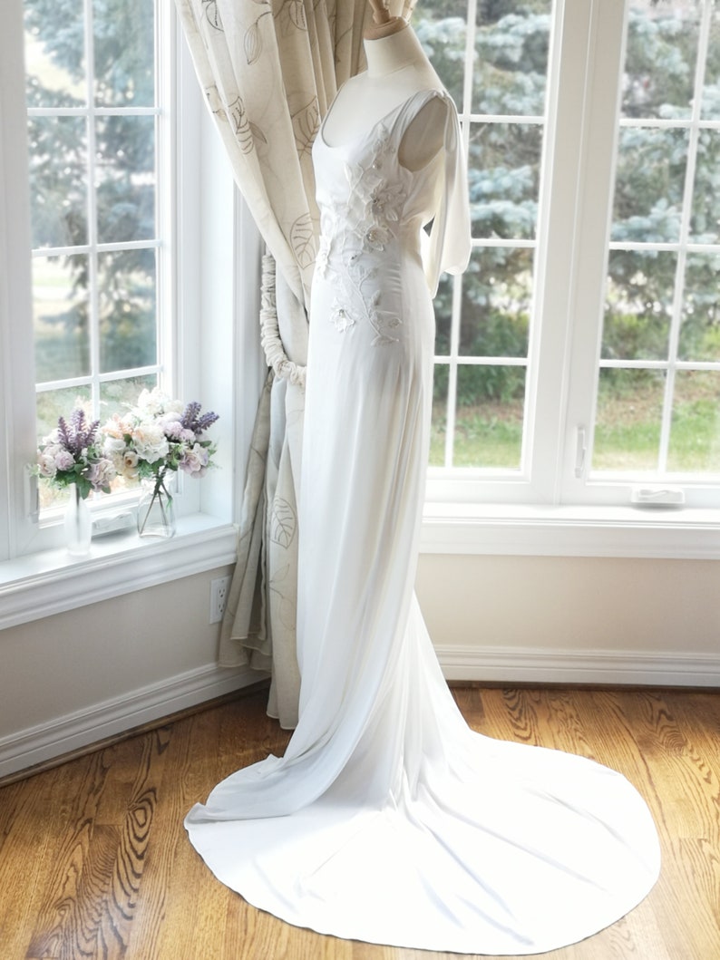 May include: A white wedding dress with a long train and floral embroidery on the bodice.