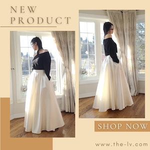 Op de afbeelding: Een zwarte off-the-shoulder top gecombineerd met een lange, ivoorkleurige rok. De rok heeft een hoge taille en een volle, vloeiende silhouet. De tekst "NIEUW PRODUCT" en "SHOP NU" is inbegrepen.