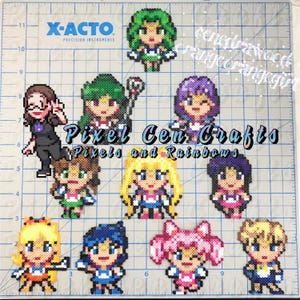 Op de afbeelding: Een verzameling van 10 pixel art-ambachten met personages uit de anime Sailor Moon. De personages zijn allemaal in hun iconische matrozenoutfits en poses. De ambachten zijn gemaakt met kleurrijke kralen en worden weergegeven op een rasterachtergrond.