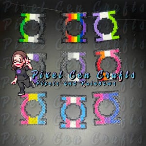 May include: A selection of pixel art designs in a circular shape, showcasing different pride flag colour schemes. The image includes the text "Pixel Cen Crafts Pixels and Rainbows".