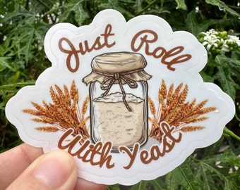 May include: White sticker with brown text that reads "Just Roll With Yeast". A drawing of a jar of yeast with wheat stalks on either side.