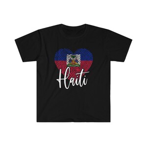 Op de afbeelding: Zwart T-shirt met een wit hartvormig vingerafdrukdesign met de kleuren van de Ha&iuml;tiaanse vlag en het woord "Ha&iuml;ti" in witte tekst.