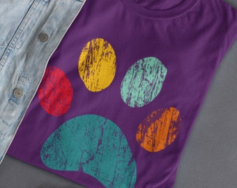 May include: Purple t-shirt featuring a colourful paw print design. The paw print is made up of five circles in shades of yellow, green, red, and orange.