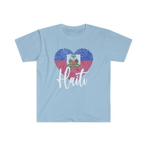Op de afbeelding: Lichtblauw T-shirt met een wit hartvormig vingerafdrukdesign met de Ha&iuml;tiaanse vlag. De tekst "Ha&iuml;ti" is in wit onder het hart gedrukt.