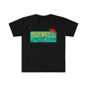 May include: Black t-shirt with a vintage-style graphic of a UFO flying over a blue and green license plate that reads "Roswell, New Mexico".