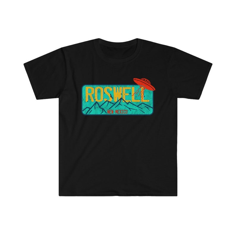 May include: Black t-shirt with a vintage-style graphic of a UFO flying over a blue and green license plate that reads "Roswell, New Mexico".