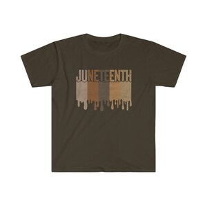 May include: A brown t-shirt with the word "Juneteenth" printed in white letters. The letters are dripping with brown, tan, and light brown paint.