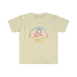 Op de afbeelding: Een lichtgeel T-shirt met een kleurrijk Leeuw-sterrenbeeld en de tekst "Trots. Gedurfd. Ambitieus. Zelfverzekerd. 23 juli - 22 augustus. LEEUW".