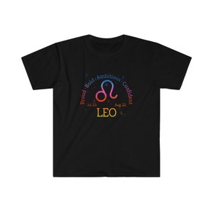 Op de afbeelding: Zwart T-shirt met een kleurrijk Leo-sterrenbeeld en de tekst "Trots, gedurfd, ambitieus, zelfverzekerd" rond het teken. De data "Jul 23" en "Aug 22" zijn ook opgenomen.
