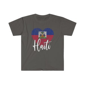 Op de afbeelding: Een donkergrijs T-shirt met een wit hartvormig ontwerp met de Ha&iuml;tiaanse vlag. De tekst "Ha&iuml;ti" is in wit onder het hart gedrukt.
