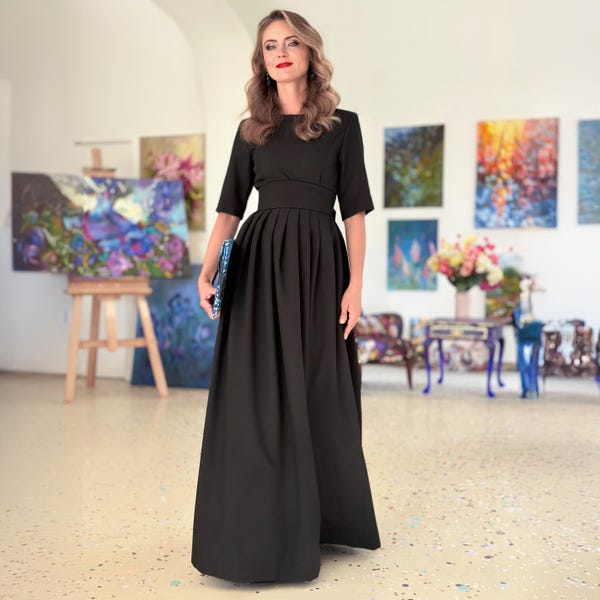 Könnte beinhalten: Ein schwarzes Maxikleid mit einem figurbetonten Oberteil und einem plissierten Rock. Das Kleid hat einen Gürtel in der Taille und Dreiviertelärmel.