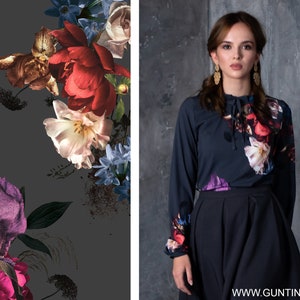May include: A dark blue long-sleeved blouse with a floral print featuring red, white, and purple flowers. The blouse has a lace-up detail at the neckline and is paired with a dark blue skirt.