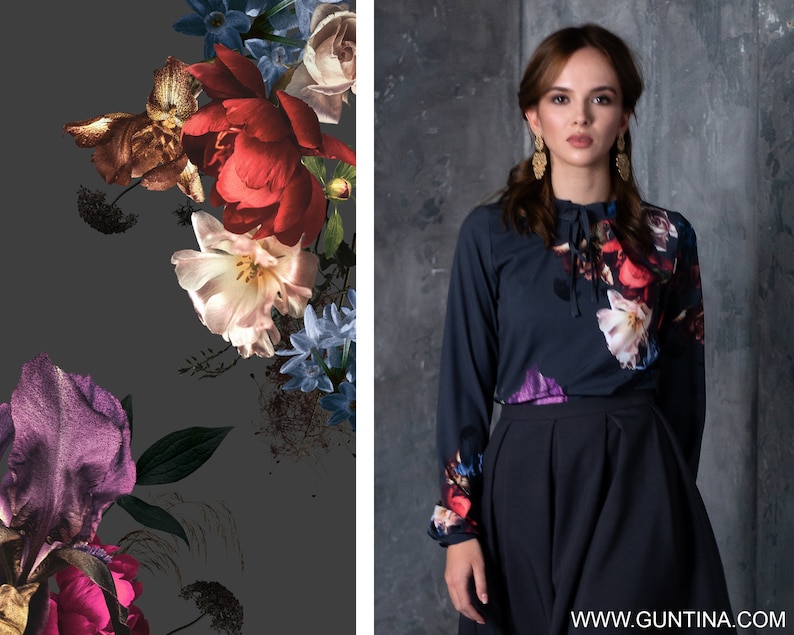 May include: A dark blue long-sleeved blouse with a floral print featuring red, white, and purple flowers. The blouse has a lace-up detail at the neckline and is paired with a dark blue skirt.
