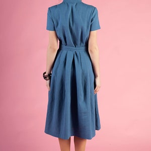 May include A blue midi dress with a belted waist and short sleeves. The dress is made of a lightweight fabric and has a flowy silhouette.