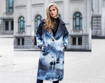 May include: A long, blue coat with a white and blue abstract print. The coat has a collar, a button closure, and pockets.