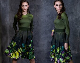 May include: A green dress with a floral print skirt. The dress has long sleeves and a fitted bodice. The skirt is full and flowing.