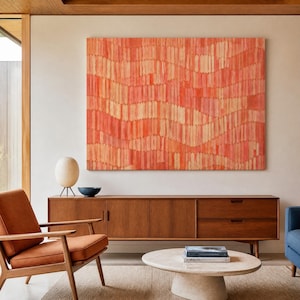 May include: An abstract artwork in red and peach tones is displayed above a wooden cabinet. A tan armchair and a round coffee table with books are in the foreground. A paper lantern lamp and a blue bowl are on the cabinet. The cabinet is 180 cm long.
