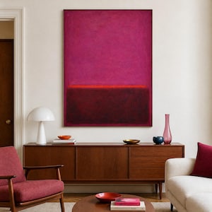 Puede incluir: Una gran pintura abstracta con una combinación de colores rojo oscuro y magenta domina la imagen. Una fina línea horizontal de rojo brillante separa los dos bloques de color principales. Un mueble de madera de estilo moderno y una silla roja están en primer plano.