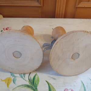 May include: Two wooden candle holders with round bases. The bases are plain and light brown. The candle holders are made of wood and have a simple design.