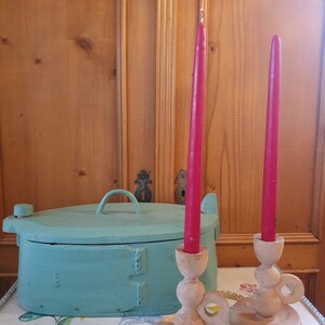May include: Two wooden candle holders with red candles, and a teal painted wooden box with a lid on a floral tablecloth.