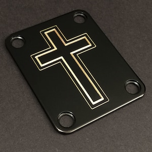 May include: Black guitar plate with four screw holes and a gold cross design.