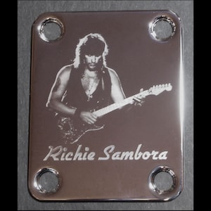 Pode incluir: Um pickguard de guitarra prateado com uma foto em preto e branco de Richie Sambora tocando guitarra. O pickguard tem quatro furos para parafusos.