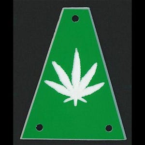 Könnte beinhalten: Grüner dreieckiger Anhänger mit einem weißen Cannabisblatt-Design. Der Anhänger hat drei kleine Löcher und einen weißen Rand. Der Hintergrund ist schwarz.