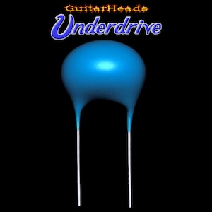 Op de afbeelding: Een blauwe keramische condensator met twee zilveren aansluitingen. De condensator heeft de vorm van een koepel met een afgeronde bovenkant. De tekst "GuitarHeads Underdrive" is geschreven in een gestileerd lettertype boven de condensator.