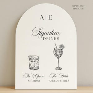 May include: An arch-shaped sign with the text "Signature Drinks" and illustrations of two cocktails. The sign includes the text "The Groom" and "The Bride" with the drink names "Negroni" and "Aperol Spritz". The sign is 5.5 x 8.5 inches.