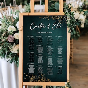 May include: A dark green chalkboard with gold glitter accents displays a wedding seating chart for Carter & Eli. The chart lists guest names by table number.