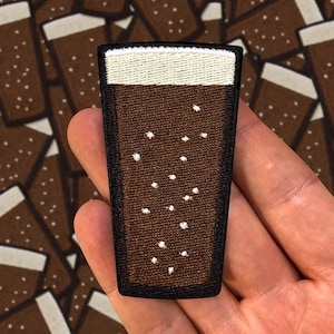 Könnte beinhalten: Ein gestickter Aufnäher, der ein Glas Bier mit weißem Schaumkopf in Braun darstellt.