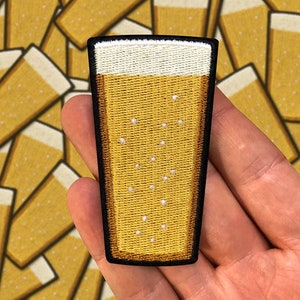 May include: An embroidered patch depicting a glass of beer with a white foam head, in yellow.