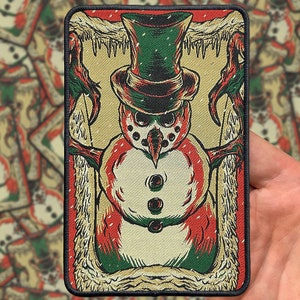 May include: A black and white illustration of a snowman with a green hat and a red and white striped scarf. The snowman is surrounded by a white frame with a brown and white pattern.