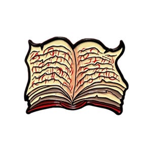 May include: An open book with a red spine and yellow pages filled with red writing. The book is made of metal and has a black outline.
