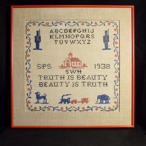 May include: A framed cross-stitch sampler on beige fabric featuring a blue and red floral border, the alphabet, a house, a train, an elephant, a dog, the initials SPS and SWH, the year 1938, and the text TRUTH IS BEAUTY BEAUTY IS TRUTH.