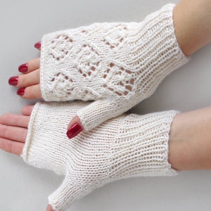 May include: A pair of white knitted fingerless gloves. One glove has a lacy pattern and the other is solid.