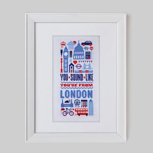 Op de afbeelding: Een wit ingelijst kruissteekontwerp met een blauw en rood kleurenschema. Het ontwerp bevat iconische Londense bezienswaardigheden en de tekst "You sound like you're from London".
