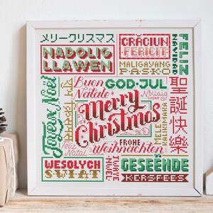 May include: A framed cross-stitch artwork with the words "Merry Christmas" in a variety of languages. The design features red, green, and gold lettering on a white background, perfect for holiday decor.