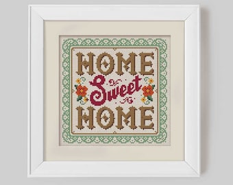 May include: A framed cross-stitch with a green border and the text "HOME Sweet HOME" in brown and red lettering. The text is surrounded by small red and yellow flowers.