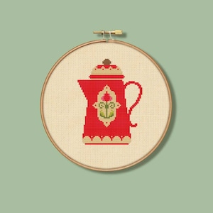 May include: Red and cream colored ceramic teapot with a floral design on the front. The teapot is in a wooden embroidery hoop.