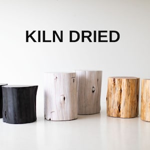 May include: Five wooden stumps, each with a different finish. Two are black, two are white, and one is natural wood. The stumps are all kiln dried. "KILN DRIED" is written in black text above the stumps.