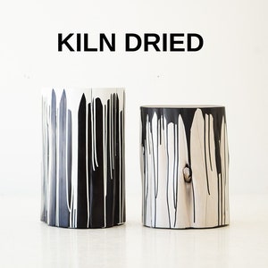 May include: Two black and white painted wooden stools with a natural wood grain. The stools are kiln dried and have a unique, abstract design.