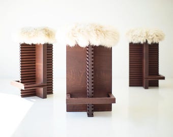 May include: Three wooden bar stools with a dark brown finish and a white faux fur seat cushion.