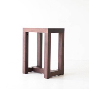 Puede incluir: Una mesa auxiliar de madera marr&oacute;n oscuro con una tapa rectangular y un dise&ntilde;o de marco simple y abierto.