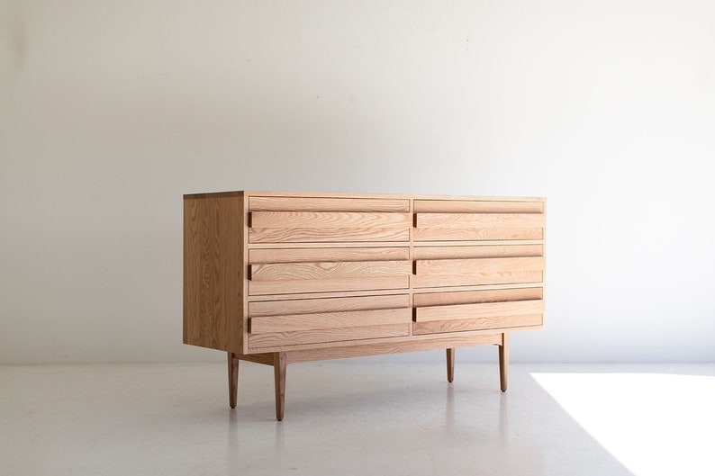 May include: A light wood dresser with six drawers and four legs. The dresser has a simple, modern design.