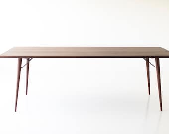 Puede incluir: Una mesa rectangular de madera con una tapa de madera marrón y cuatro patas delgadas. La mesa tiene un diseño simple y moderno.